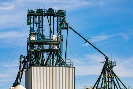 Details of a modern grain processing plant, elevator pipes connected to industrial building against...