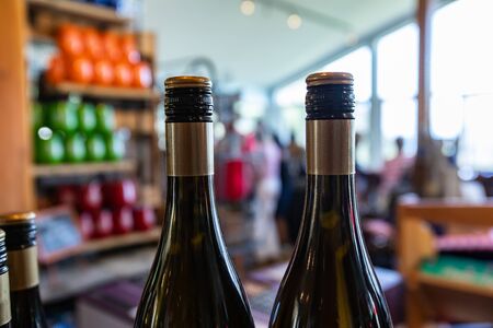 two bottles of wine top, with black and golden screw cap seal color, neck and shoulder of the bottle closeup selective focus, wines shop backgroundの写真素材