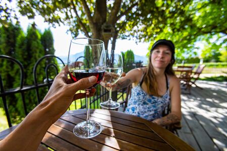 man and woman toasting red and white wine glasses selective focus, winery restaurant terrace, man...