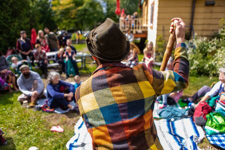 Closeup rear view of male wearing sun hat and colorful checked shirt telling fairytale story to...