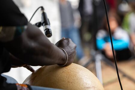 Midsection of african male professional musician playing calabash on stage during event in city at...