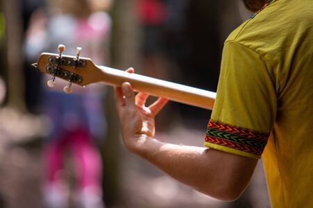 Closeup midsection of man wearing fancy colorful t-shirt while playing wooden merlin outdoors during...
