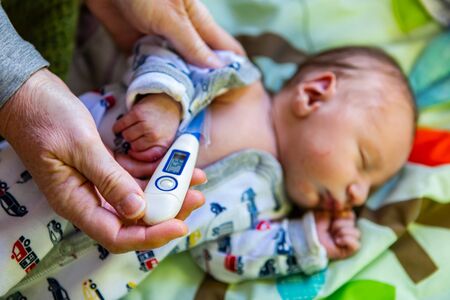 A close up selective focus view on the hands of a family doctor using a medical thermometer under...