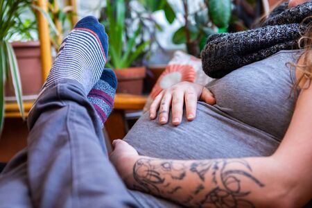 A closeup shot on the feet of a man resting over heavily pregnant partner with large swollen stomach...