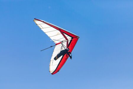 Hang glider soaring against the clear blue sky. View from the bottom to flying hang glider pilot....