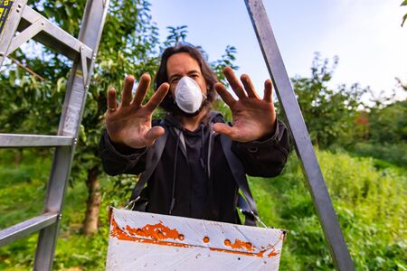 Professional cherry-picker with a respirator in the industrial cherry garden. Front view of the...