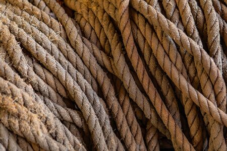A pile of aged sailing ropes. Close-up view of old knots used in fishing and safety industry. Selective focus. Rope backgroundの写真素材