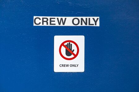 Black lettered signboard on blue background saying Crew Only. Warning sign on the command bridge of a passenger ferry navigating in a canadian lake.の写真素材