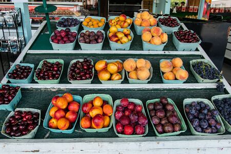 Close up of neatly arranged green cardboard boxes of colorful and shiny mixed fruit.Local food market ambient in the background. Variety of choice.の写真素材