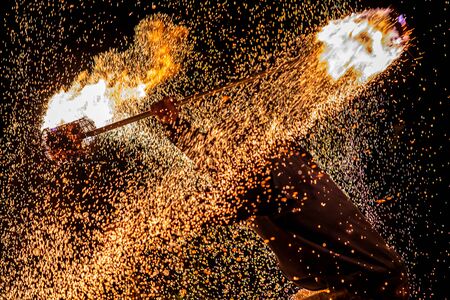 A close up action shot of a fire dancer during a night performance with a flaming lance. with...