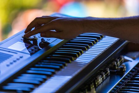 A close up selective focus shot of a person playing an electronic keyboard on stage at a music festival, with blurry keys in foreground and copy spaceの写真素材