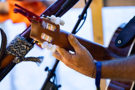 A closeup selective focus side view on the hand of a guitarist as a traditional band play on stage at a multicultural festival, with copy spaceの写真素材