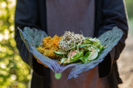 A close up selective focus shot of health vegetarian food served on a collard leaf, mixed and chopped salad greens and vegetables served at earth festivalの写真素材
