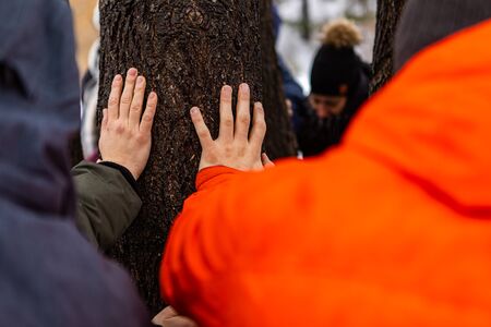 A group of people from the environmental movement gathered around a tree and put their hands on it. The standing around a tree menの写真素材