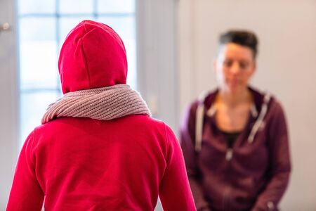 Rear view of a person who practices yoga with an individual trainer. The woman in a red hood taking...