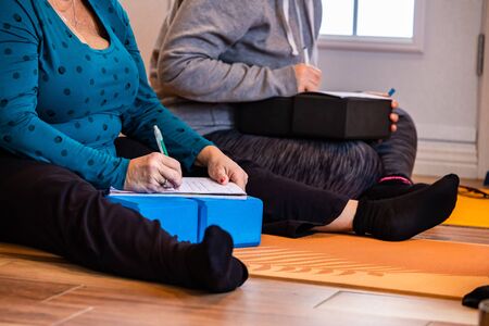 The married couple taking notes during yoga class. The studying yoga people through making notes on a notepad. A writing man and a womanの写真素材