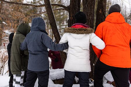The fighters for ecology who stand around a tree in winter on the snow holding hands. The nature...