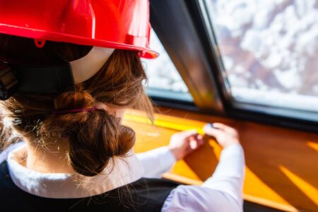 close up on female construction inspector wearing red hard hat as she checking the window using a tape measure, inspecting eco energy efficient home.の写真素材
