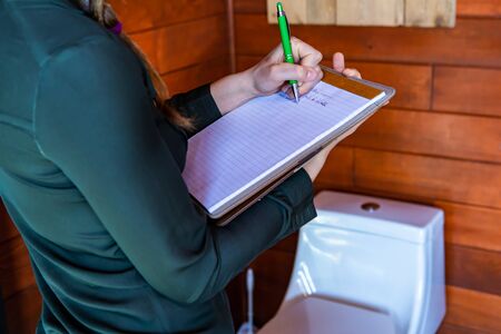 Woman construction inspector inspecting a house bathroom. close up, selective focus on her clipboard...