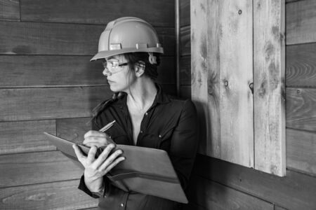 inspector woman taking notes on clipboard during Indoor air quality inspection she looking for molds, fungi problems on wooden walls, black and whiteの写真素材