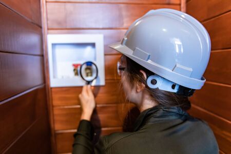selective focus on construction inspector woman's hand holding a magnifying glass to check hot and cold water entry for a washing machine.の写真素材