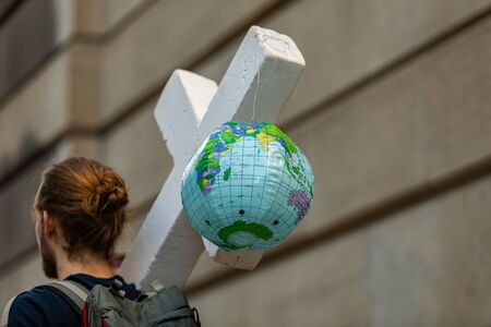 A creative cross and planet earth 3D sculpture placard is seen up close during a climate rally,...