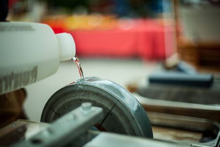 A closeup selective focus shot on a bottle of lubricating oil pouring onto a spinning wheel at a...