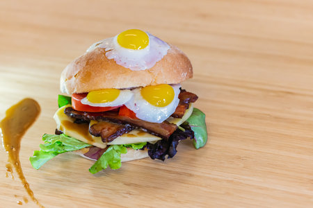 Full picture of a fully stuffed quail egg sandwich, layered with cheese and vegetables, placed neatly on a wooden kitchen shelfの写真素材