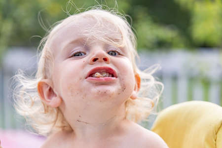 Close up fun portrait of a three year old boy with humorous personality posing with food sticking...