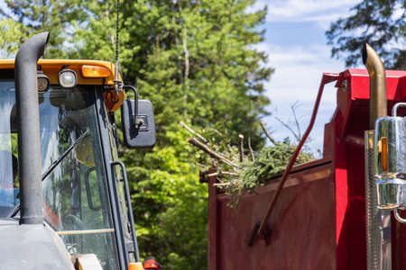 Selective focus shot on the front exhaust and windshield of an excavator, blurry dumper lorry is...