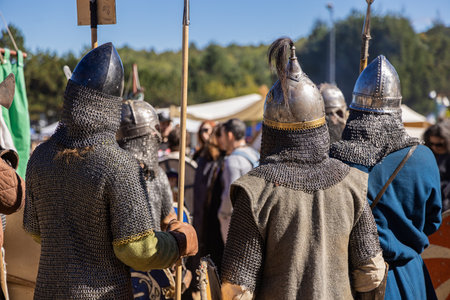 Medieval reenactors wearing chainmail armor are seen from behind holding spears while standing in a rowの写真素材