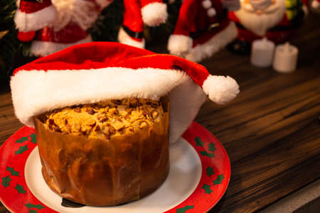 Fruit panettone covered with chestnuts in a decorated plate for Christmas on a wooden table, with...