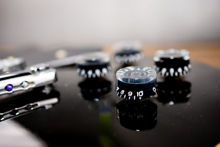 Black electric guitar with emphasis on the volume knobs. Selective focus.