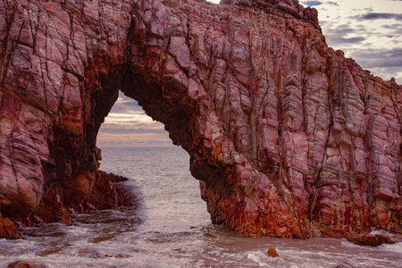 The Pedra Furada (Pierced Rock) in Jericoacoara, CearÃ¡. It is the most famous tourist spot in the area, featuring a rocky formation by the sea, with a sunset in the background.の写真素材