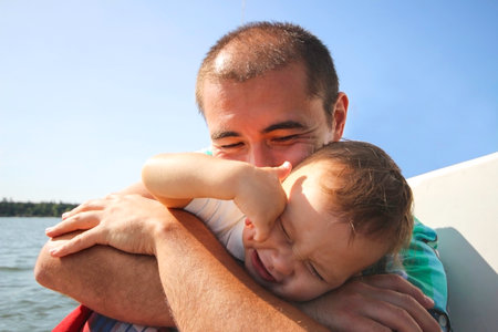 Asian man with a small child. Father and son lit by the sun on a summer day. Dad hugs his little...