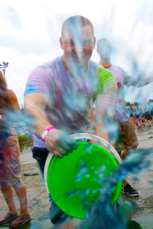 NOVOSIBIRSK, RUSSIA - JUNE 28, 2014: Color Fest. A man with a bucket of paint pulls it out on...