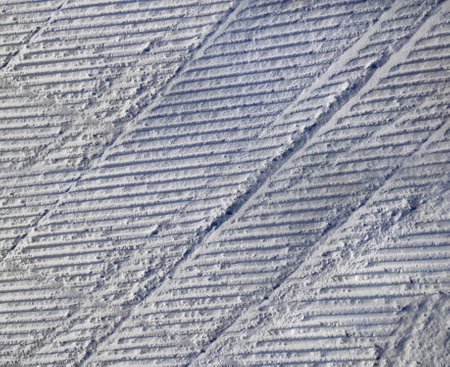 A pattern of relief footprints in the snow after cleaning the ski slope with a snowcat. Grunge knurled snow background with ski slopeの写真素材