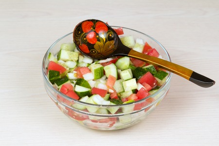 Vegetable salad with onion, tomato and cucumber with a spoonの写真素材