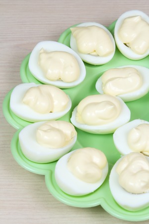 The slices of boiled chicken eggs with mayonnaise  on a green plateの写真素材