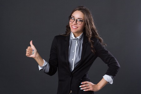 beautiful smiling girl holding thumb up, studio pictureの写真素材