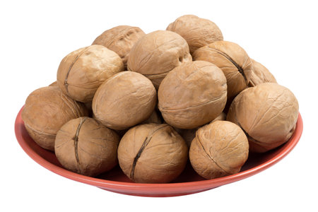 Walnuts on a brown plate isolated on white backgroundの写真素材