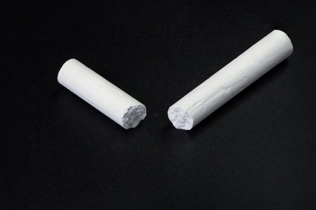 Broken white chalk on black chalk board for notesの写真素材