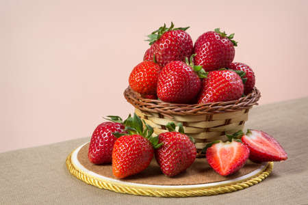 Fresh strawberries in a wicker basket on a wooden boardの写真素材