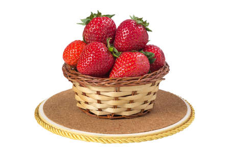 Fresh strawberries in a wicker basket on a wooden board isolated on white backgroundの写真素材