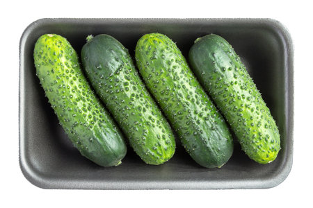 Four cucumbers in the black plastic container isolated on white backgroundの写真素材
