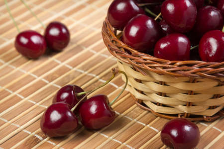 Cherry in a wicker basket on bamboo napkinの写真素材