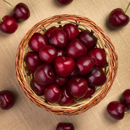 Cherry in a wicker basket on linen. View from above.の写真素材