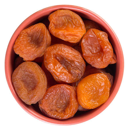 Dried apricots in brown cup isolated on white backgroundの写真素材