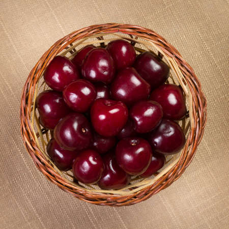 Cherry in a wicker basket on linen. View from above.の写真素材