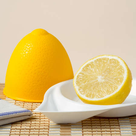 Half fresh lemon in a lemon plastic bowl on bamboo napkinの写真素材